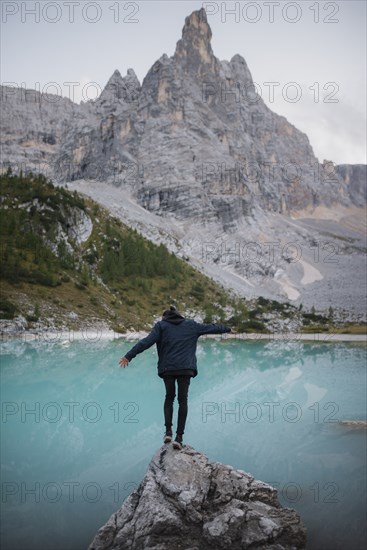 Italy, South Tyrol, Cortina d Ampezzo, lake Sorapis, Man standing on top of rock catching balance