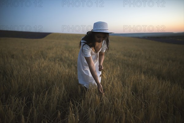 France, Woman in white dress and hat in field