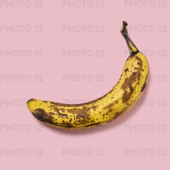 Overripe banana on pink background