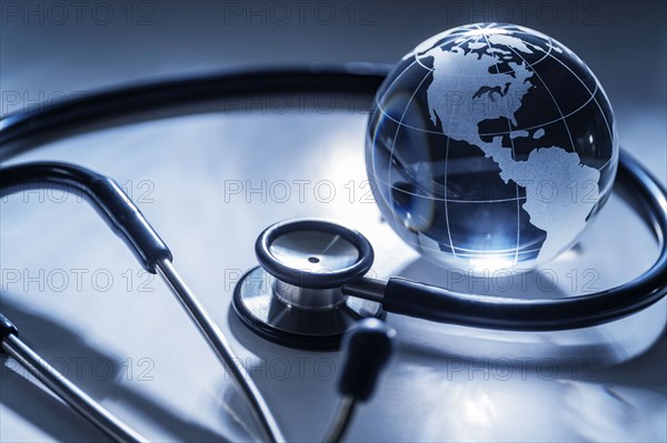 Glass globe and stethoscope on gray background