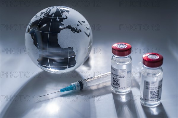 Glass globe and syringe with vaccine on gray background