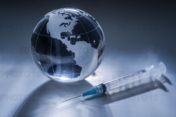 Glass globe and syringe on gray background