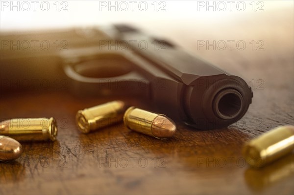 Gold bullets and pistol on wooden surface