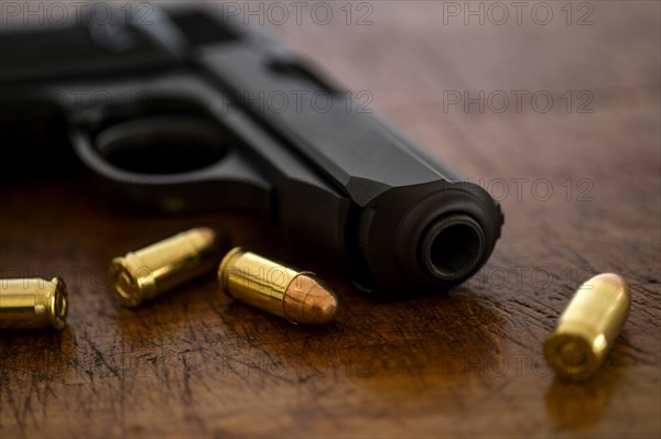Gold bullets and pistol on wooden surface
