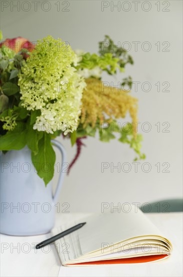 Notepad and flower bouquet on table