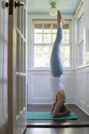 Woman doing headstand on mat