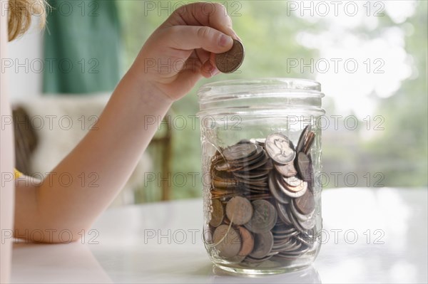 Boys (4-5) hand putting coins into jar