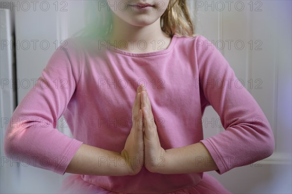 Midsection of girl (6-7) with hands clasped