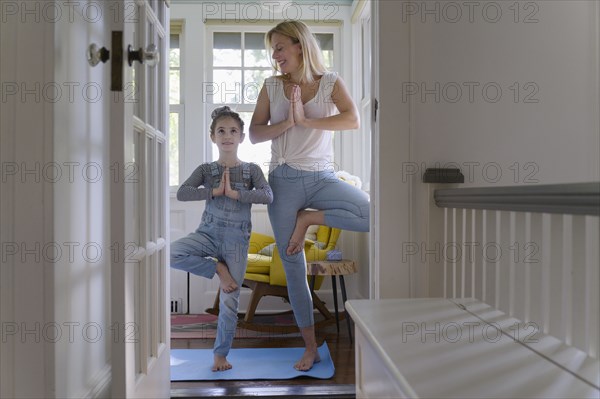 Mother with daughter (6-7) practicing yoga together at home