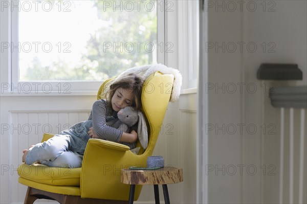 Girl (5-7) relaxing in armchair