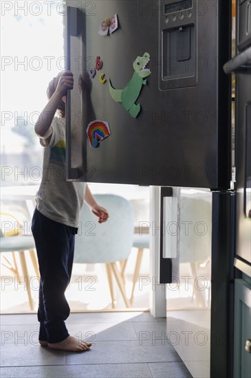 Boy (4-5) searching for food in fridge