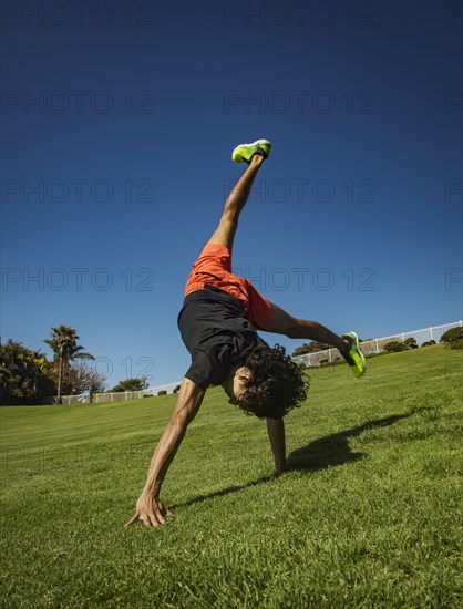 Man doing cartwheel on grass