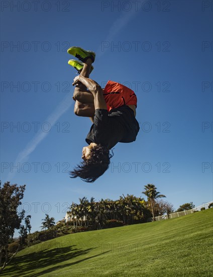 Man doing back flip over grass