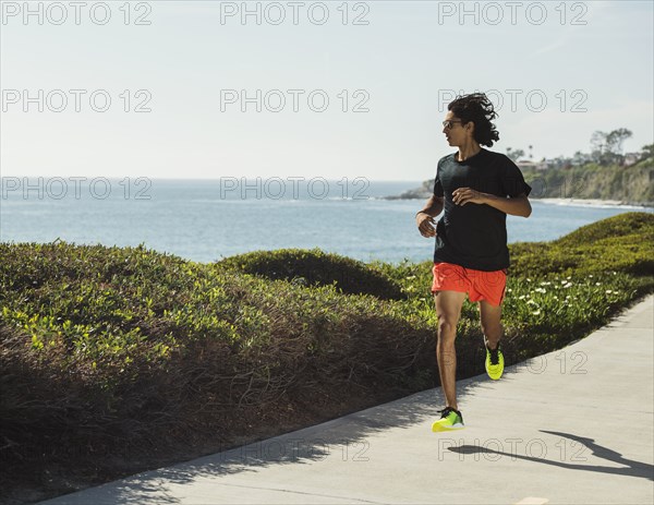 USA, California, Dana Point, Man running on road by coastline