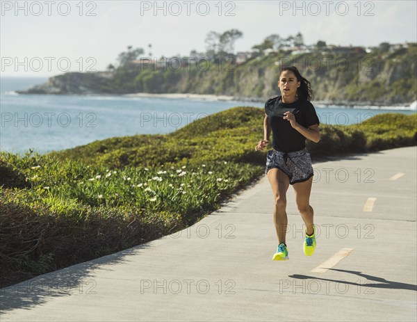 USA, California, Dana Point, Woman running on road by coastline