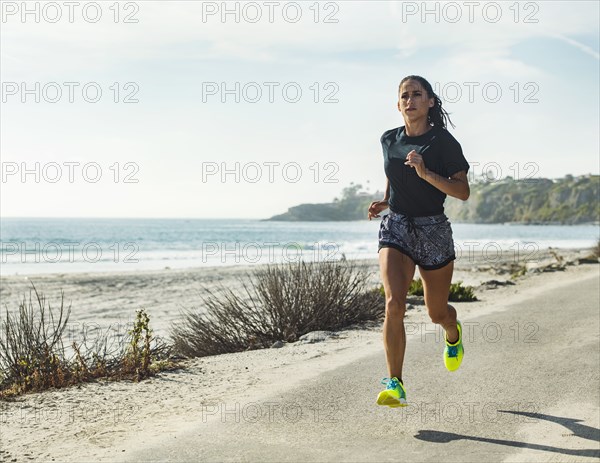 USA, California, Dana Point, Woman running on road by coastline