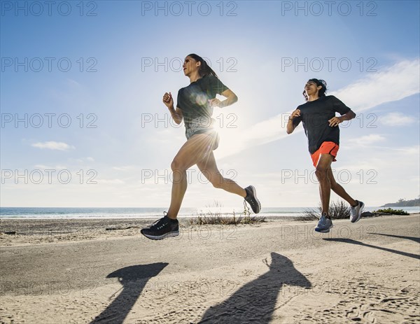 USA, California, Dana Point, Man and woman running together by coastline