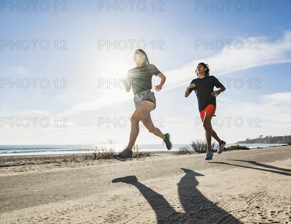 USA, California, Dana Point, Man and woman running together by coastline