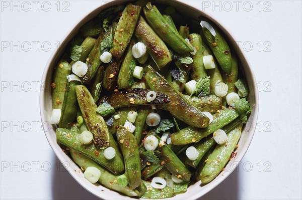 Cooked green peas with scallions and red pepper flakes