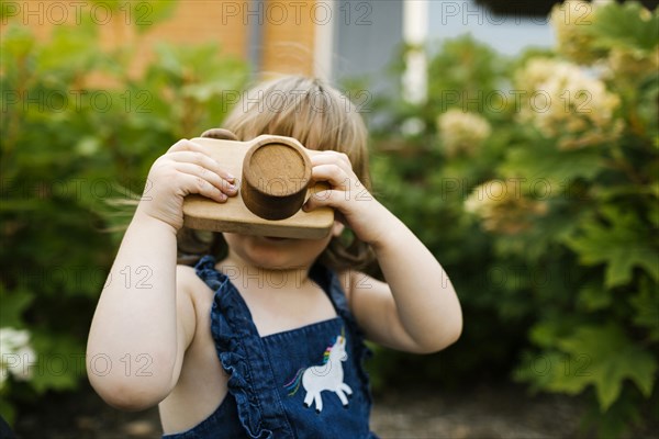 Toddler girl (2-3) with toy camera in garden