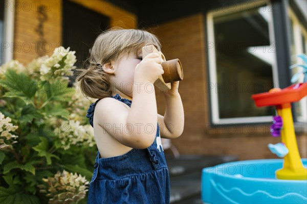 Toddler girl (2-3) with toy camera in garden