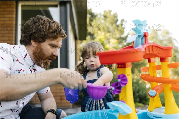 Father and toddler daughter (2-3) playing with water in garden