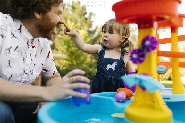 Father and toddler daughter (2-3) playing with water in garden