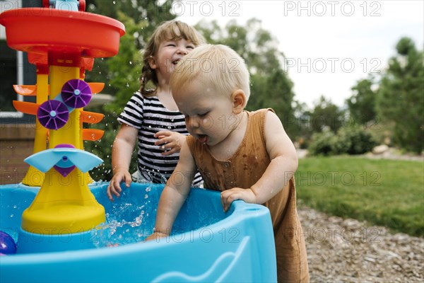 Toddler girl (2-3) and baby boy (18-23 months) playing in garden