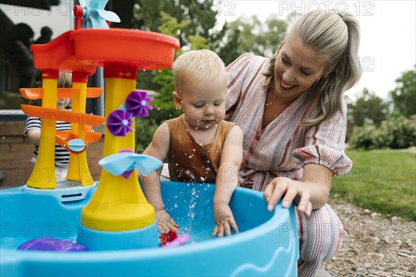 Mother with baby son (18-23 months) playing with water in garden