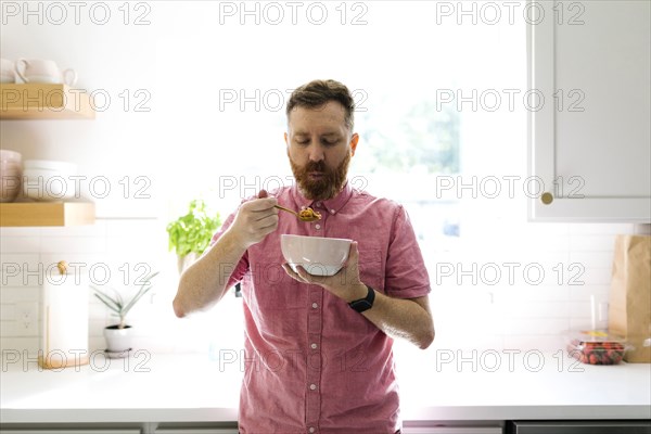 Man eating cereal breakfast in kitchen