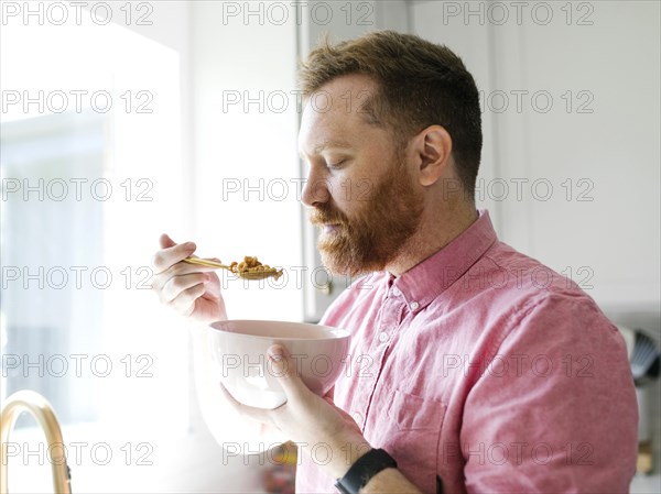 Man eating cereal breakfast in kitchen