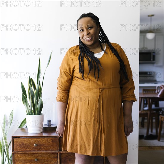 Portrait of smiling woman in orange dress at home