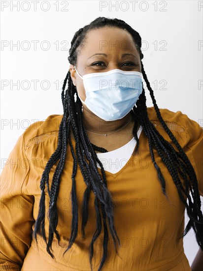 Studio portrait of woman wearing protective face mask and orange dress