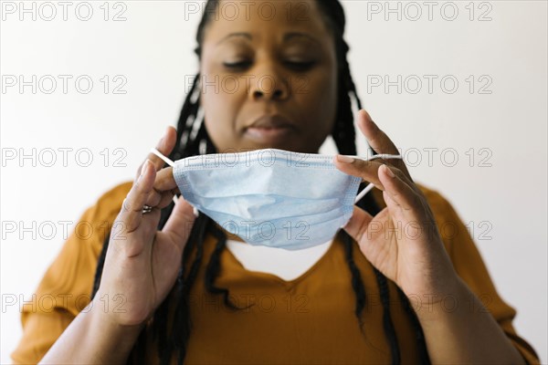 Studio portrait of woman putting on protective face mask