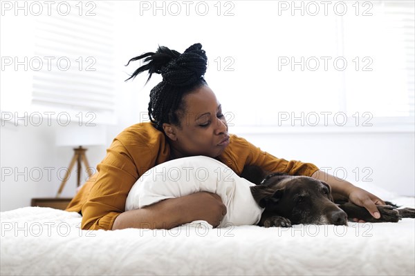 Woman lying on bed with dog