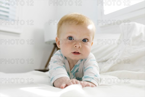 Baby boy (6-11 months) lying on bed