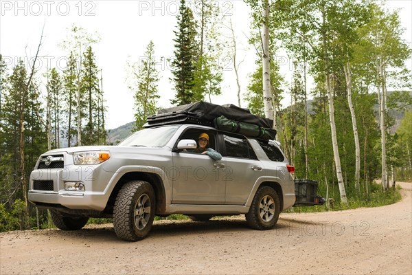 USA, Utah, Uinta National Park, Woman sitting in off road car with tent on roof