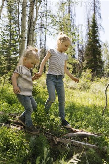 USA, Utah, Uinta National Park, Two sisters (2-3, 6-7) walking on log in forest