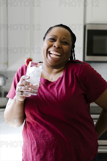 Portrait of smiling woman in purple dress holding glass of water