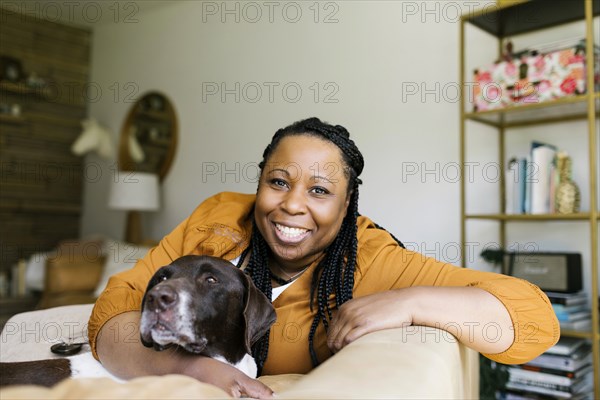 Portrait of smiling woman sitting on sofa with dog