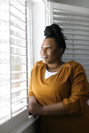 Woman in orange dress looking through window