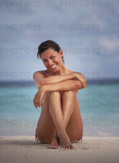 Maldives, Portrait of smiling woman sitting on beach