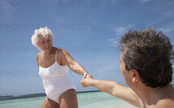 Indian Ocean, Maldives, Ari Atoll, Vilamendhoo Island, Happy couple holding hands on tropical beach