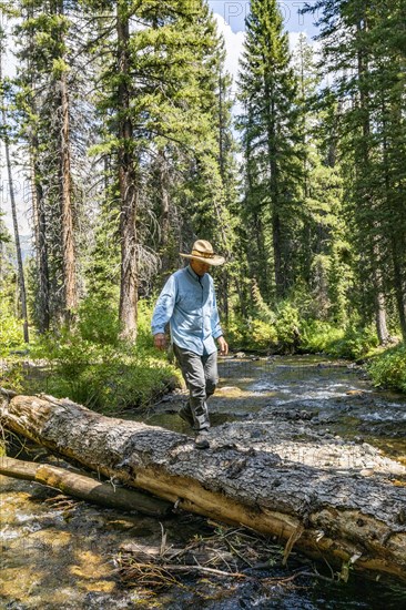 USA, Idaho, Sun Valley, Man crossing river in forest