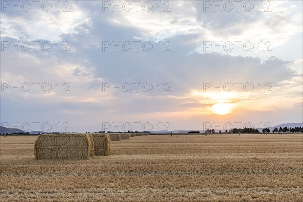 USA, Idaho, Bellevue, Bales of hay in field at sunset