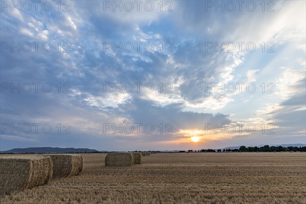USA, Idaho, Bellevue, Bales of hay in field at sunset