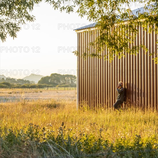 USA, Idaho, Bellevue, Farmer leaning against farm building and talking on phone