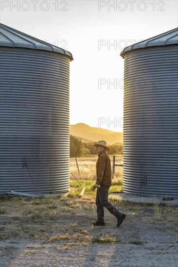 USA, Idaho, Bellevue, Rancher walking past silos