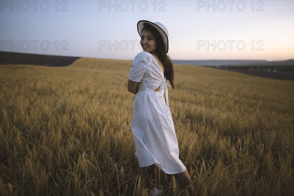 France, Young woman in white dress standing in cereal field