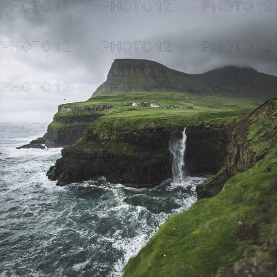 Denmark, Faroe Islands, Gasadalur village, Mulafossur Waterfall, Mulafossur Waterfall falling from cliff into ocean